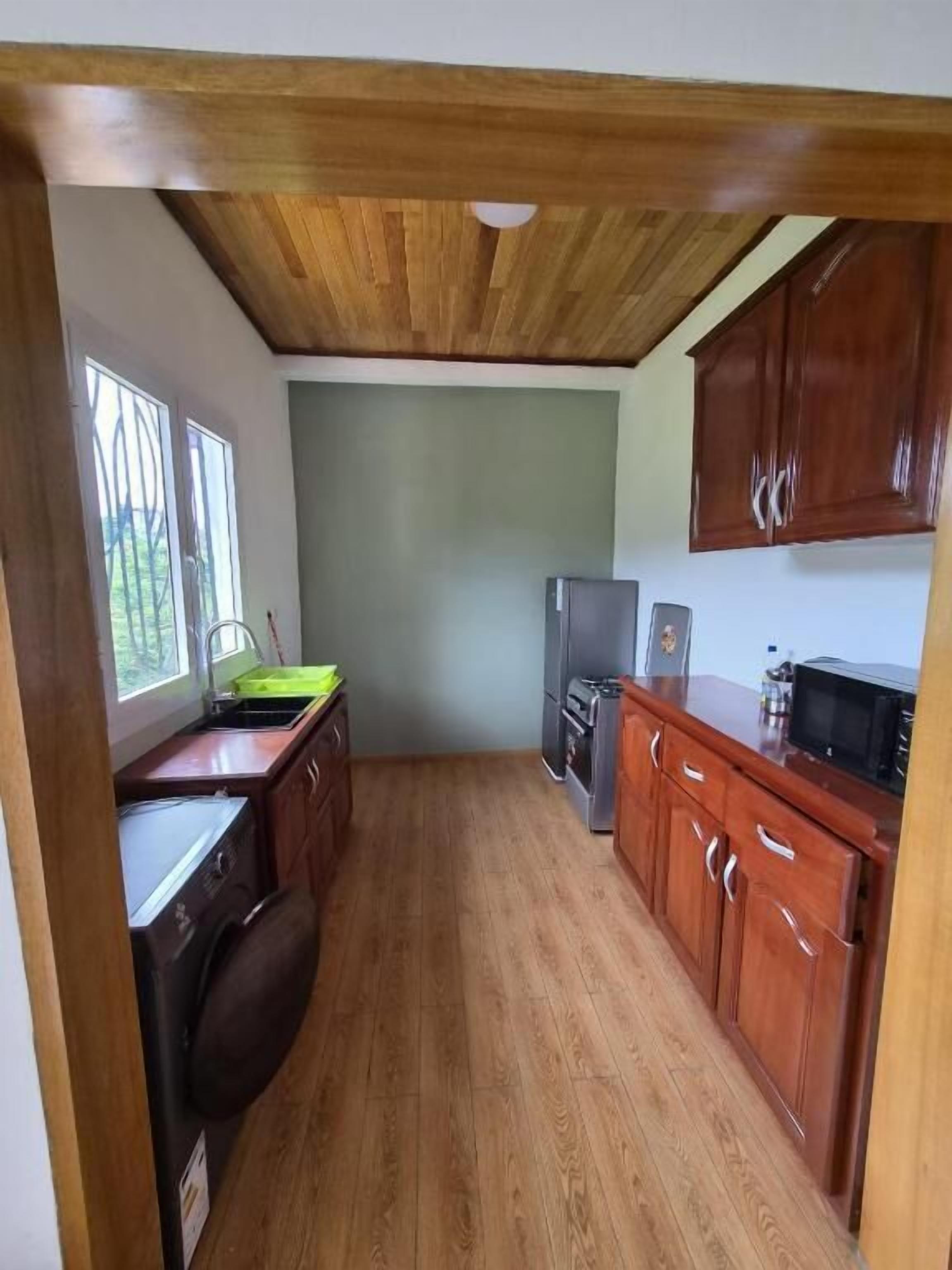 A compact kitchen with wooden cabinets, a refrigerator, and a microwave.