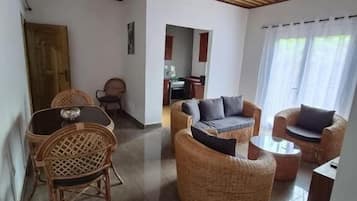 Amplia sala de estar con muebles de mimbre, techo de madera y vista a la cocina.