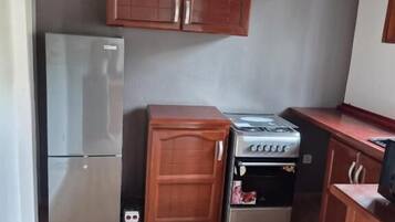 Una cocina compacta con armarios de madera, un refrigerador y una estufa.