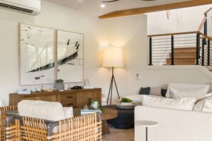 A modern living room with a sofa, a coffee table, a lamp, and a staircase. - Tranquility in Princeville (Princeville)