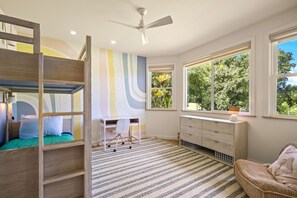 A room with a bunk bed, desk, chair, and a large window with a view of greenery. - Tranquility in Princeville (Princeville)