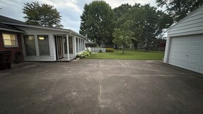 A residential garage with a concrete driveway, a white fence, and a grassy yard. - Charming Lebanon Home - SunRoom - Firepit - Sleeps 4 (Lebanon)