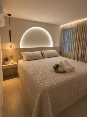 A modern bedroom with a large bed, a bedside table with a plant, and a wall-mounted light fixture. - Provenza's Top Apt w/ Jacuzzi, AC, WD, Elevator, Located in the Best Area (Medellín)