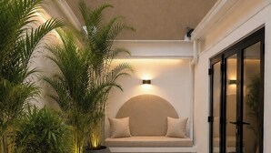 Decoração moderna com área de estar, plantas em vasos e luminária fixada na parede.