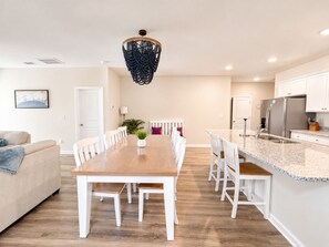 Una cocina moderna con armarios blancos, encimera de granito y una isla integrada con asientos.