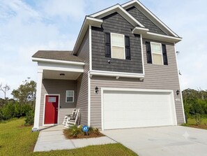 Ein zweigeschossiges Haus mit roter Tür, Garage und einem gepflegten Rasen.