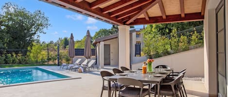 An outdoor patio with a pool, lounge chairs, and a dining table.