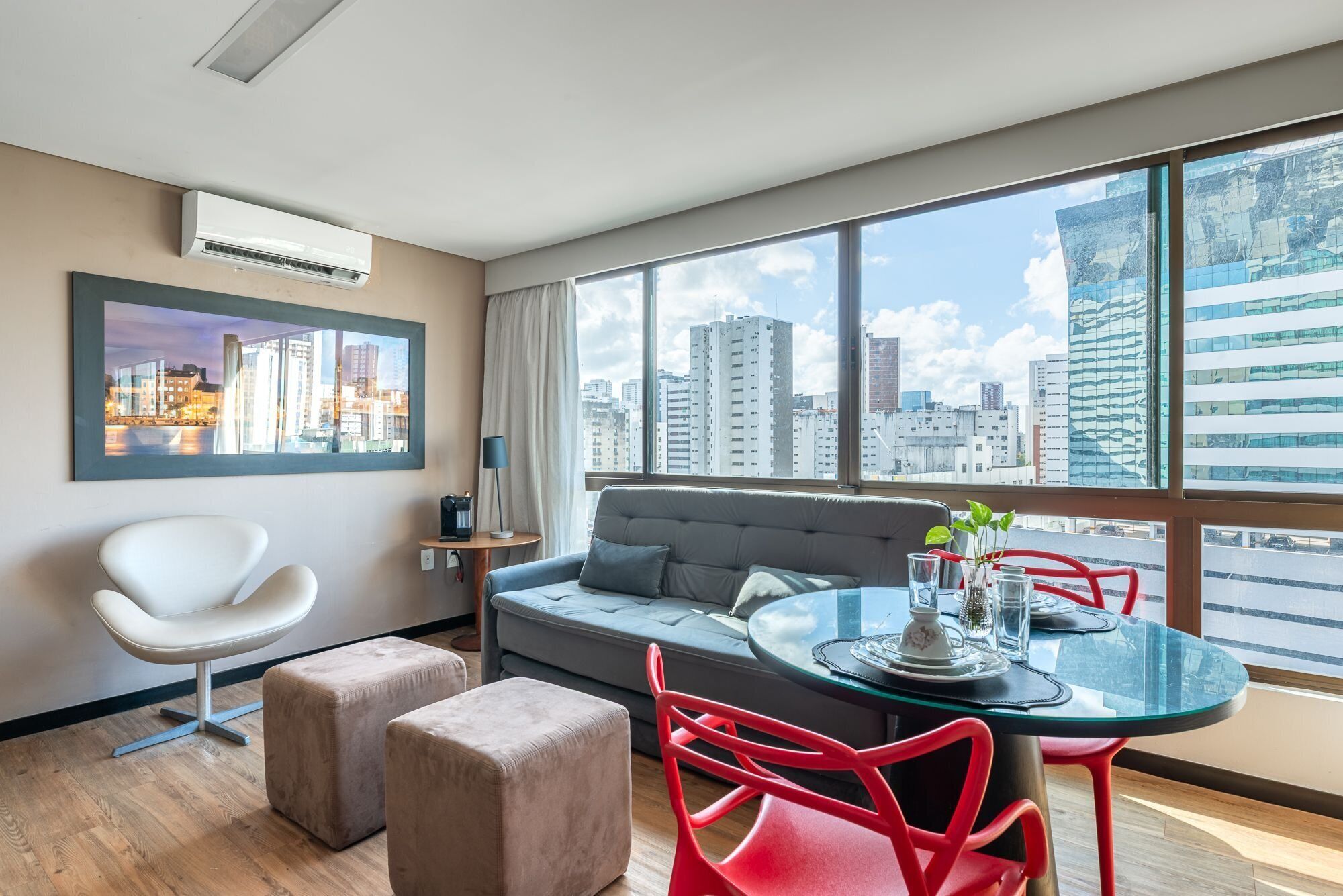 Una moderna camera d'albergo con vista sulla città, un divano, un tavolo da pranzo e una sedia.