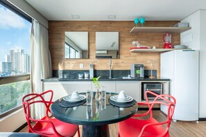 A modern kitchen with a dining area, a view of the city, and a window with curtains. - Aparament em Boa Viagem-Prox a Praia-167 (Recife)