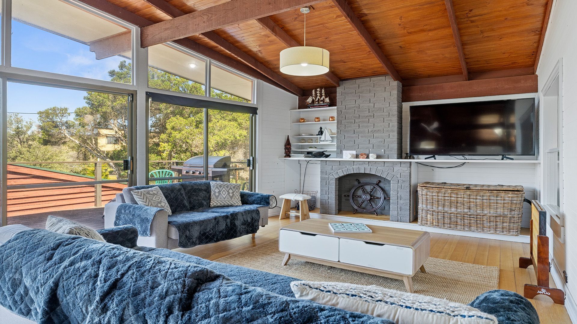 A modern living room with a fireplace, large windows, and a television.