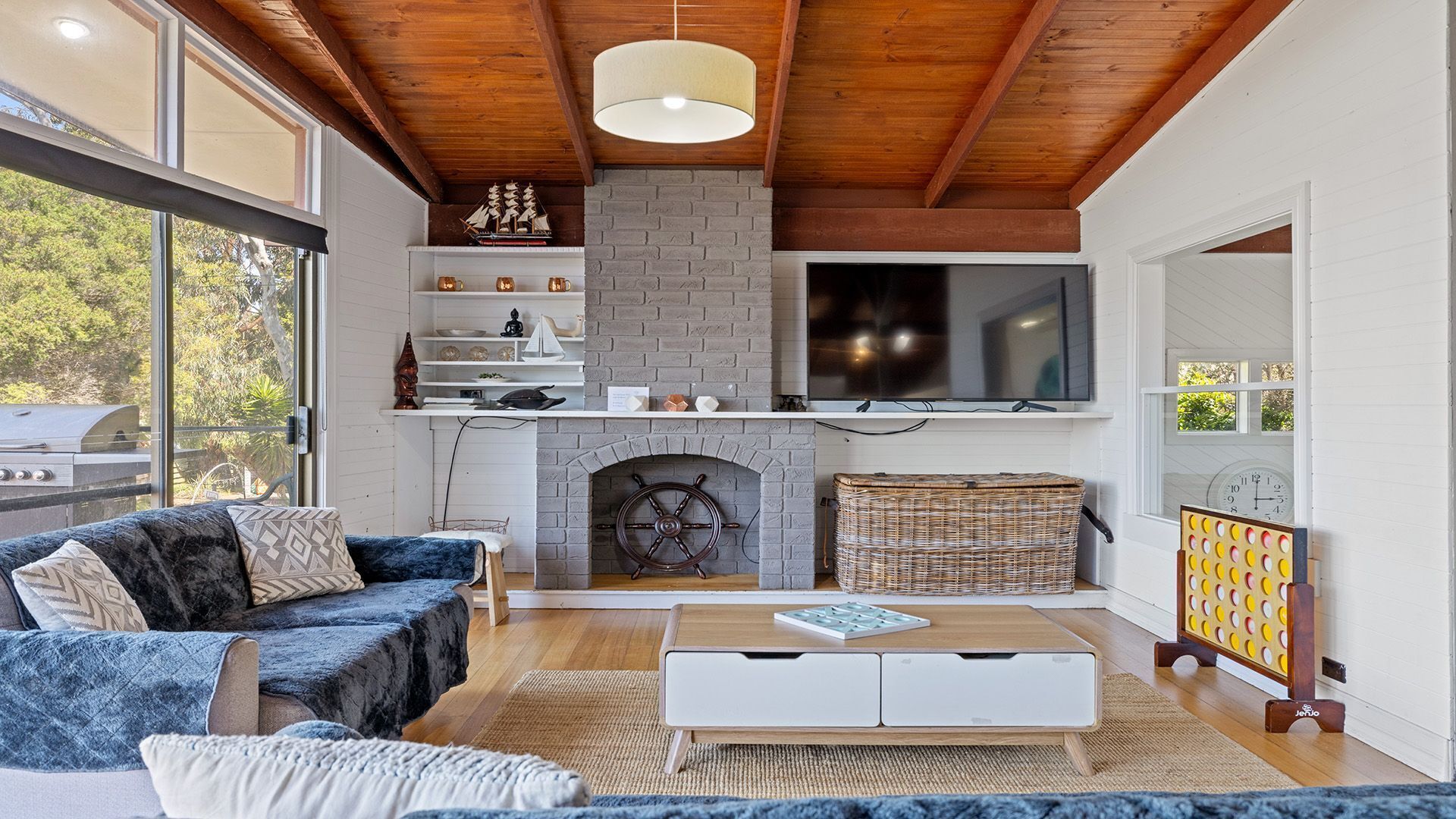Een moderne woonkamer met een open haard, een televisie en een groot raam.