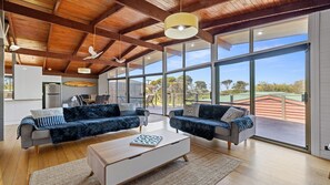 A spacious living area with two sofas, a coffee table, and large windows offering a view of the outdoors. - Coastal Calm at Cape Woolamai (Cape Woolamai)