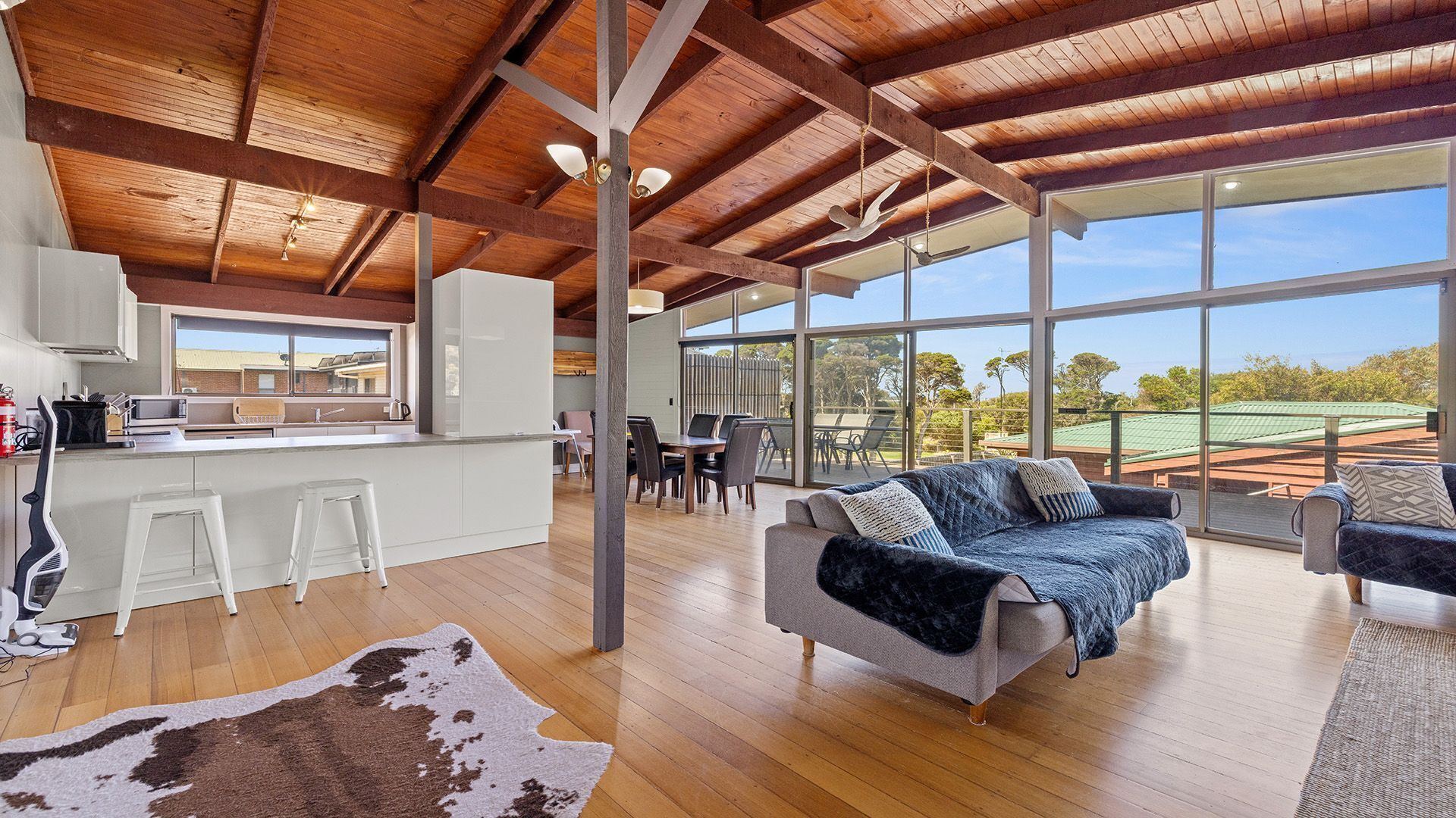 A spacious interior with a kitchen, dining area, and seating with large windows.