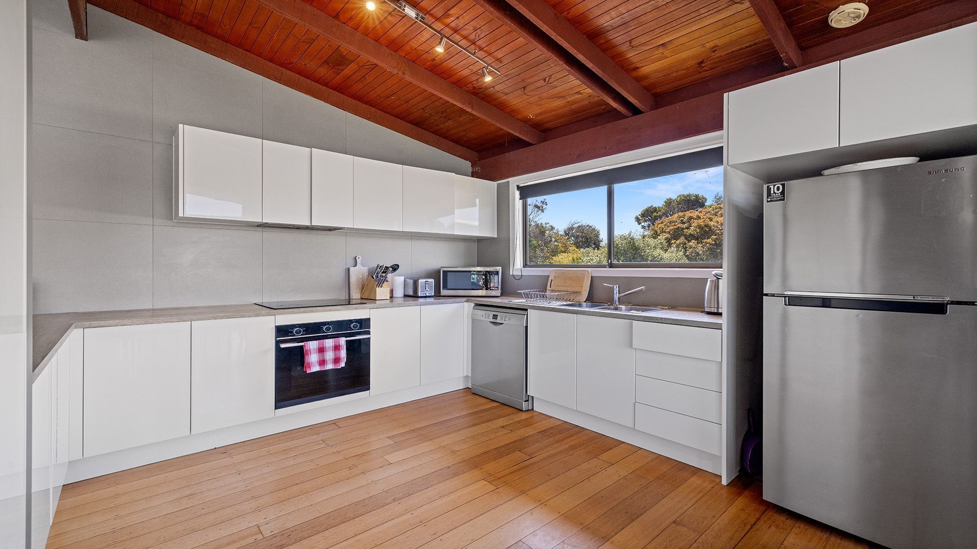 A modern kitchen with white cabinetry, a stainless steel refrigerator, a microwave, and an oven.