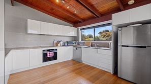 A modern kitchen with white cabinetry, a stainless steel refrigerator, a microwave, and an oven.