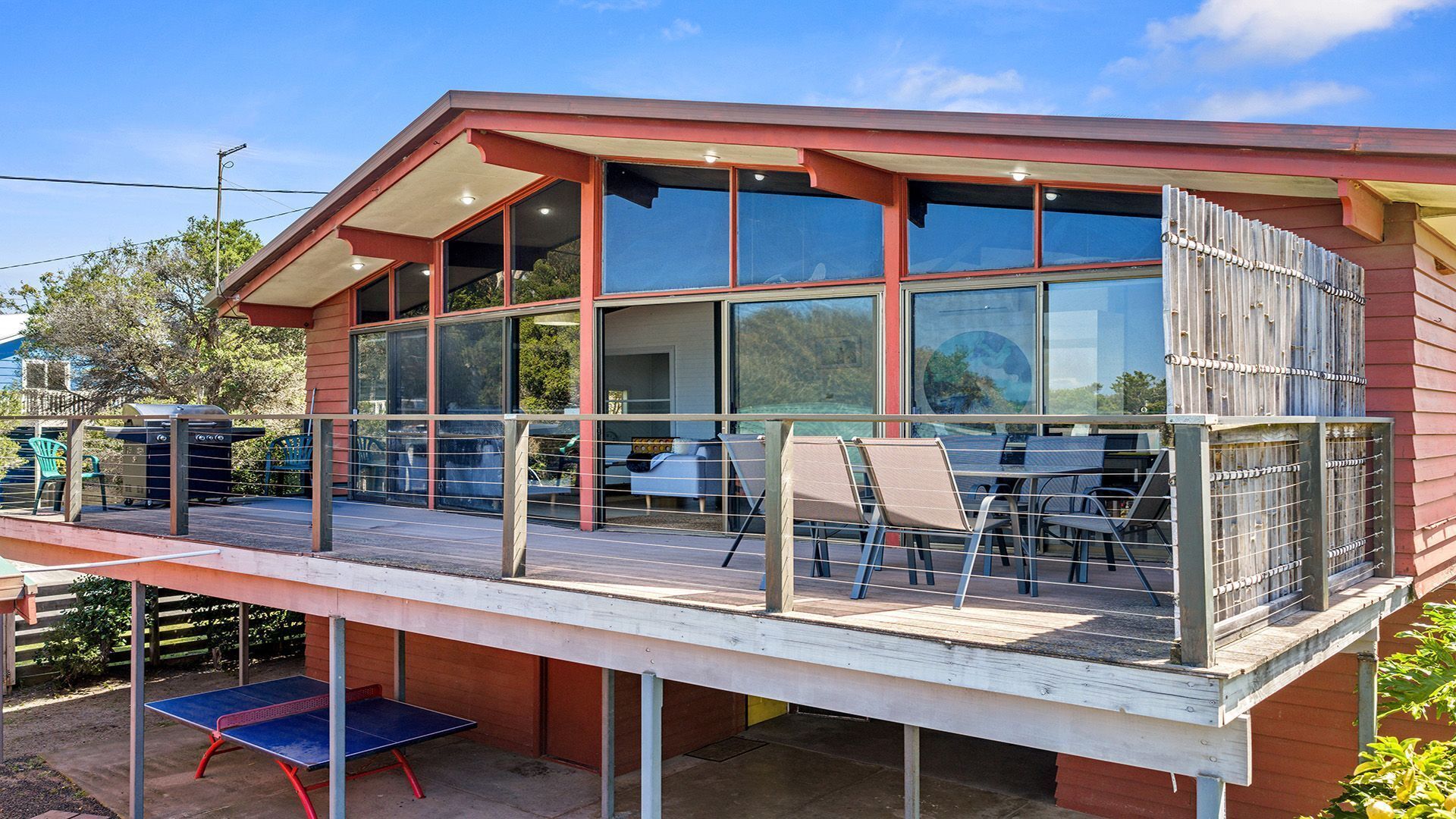 A modern house with a covered patio area featuring outdoor seating and a ping pong table.