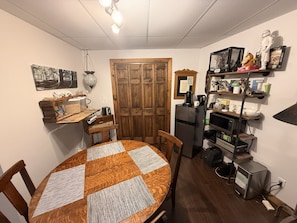 A compact kitchen with a dining table, wooden cabinets, and a refrigerator.
