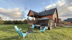 Une cabane en bois dotée d’un porche couvert, d’un barbecue et de mobilier d’extérieur.