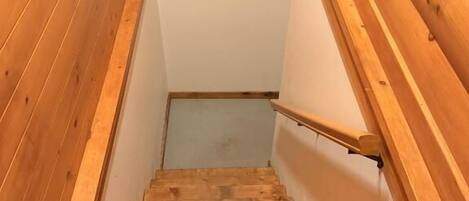 Un escalier en bois avec une rampe, des marches recouvertes de moquette et une fenêtre en haut.