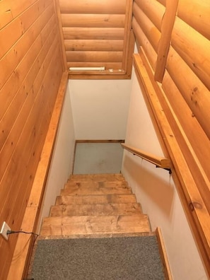 Una escalera de madera con barandilla, escalones alfombrados y un ventanal en la parte superior.