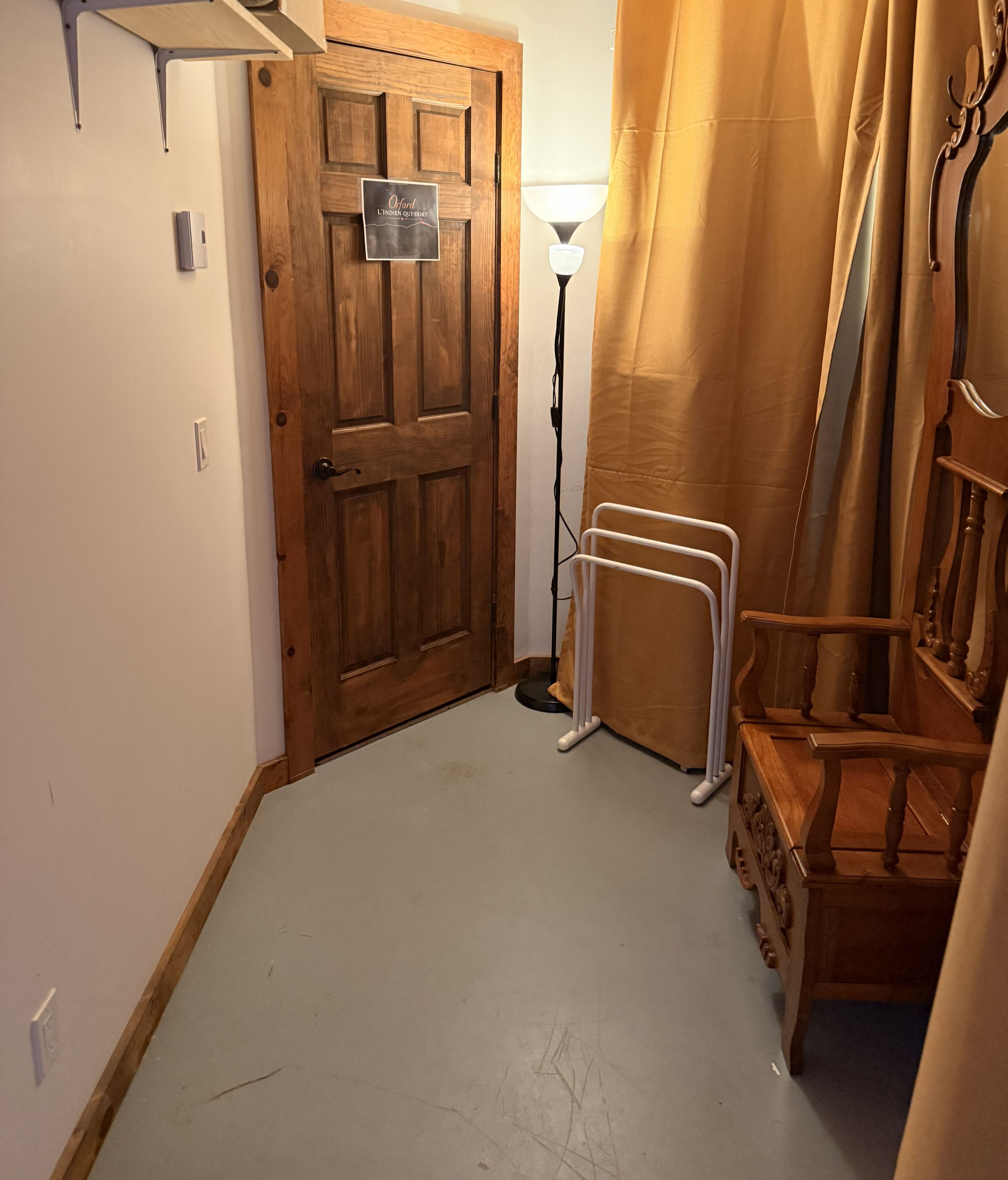 A hallway with a wooden door, a floor lamp, and a radiator.