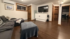 Un salon avec un canapé, un téléviseur et un meuble.
