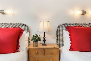 A room with two beds, each with a checkered headboard, a bedside table with a lamp, and red pillows. - 411 Beaver Creek Lodge at the Covered Bridge, Pool, Hot Tub, Gym, Steam Room (Beaver Creek)
