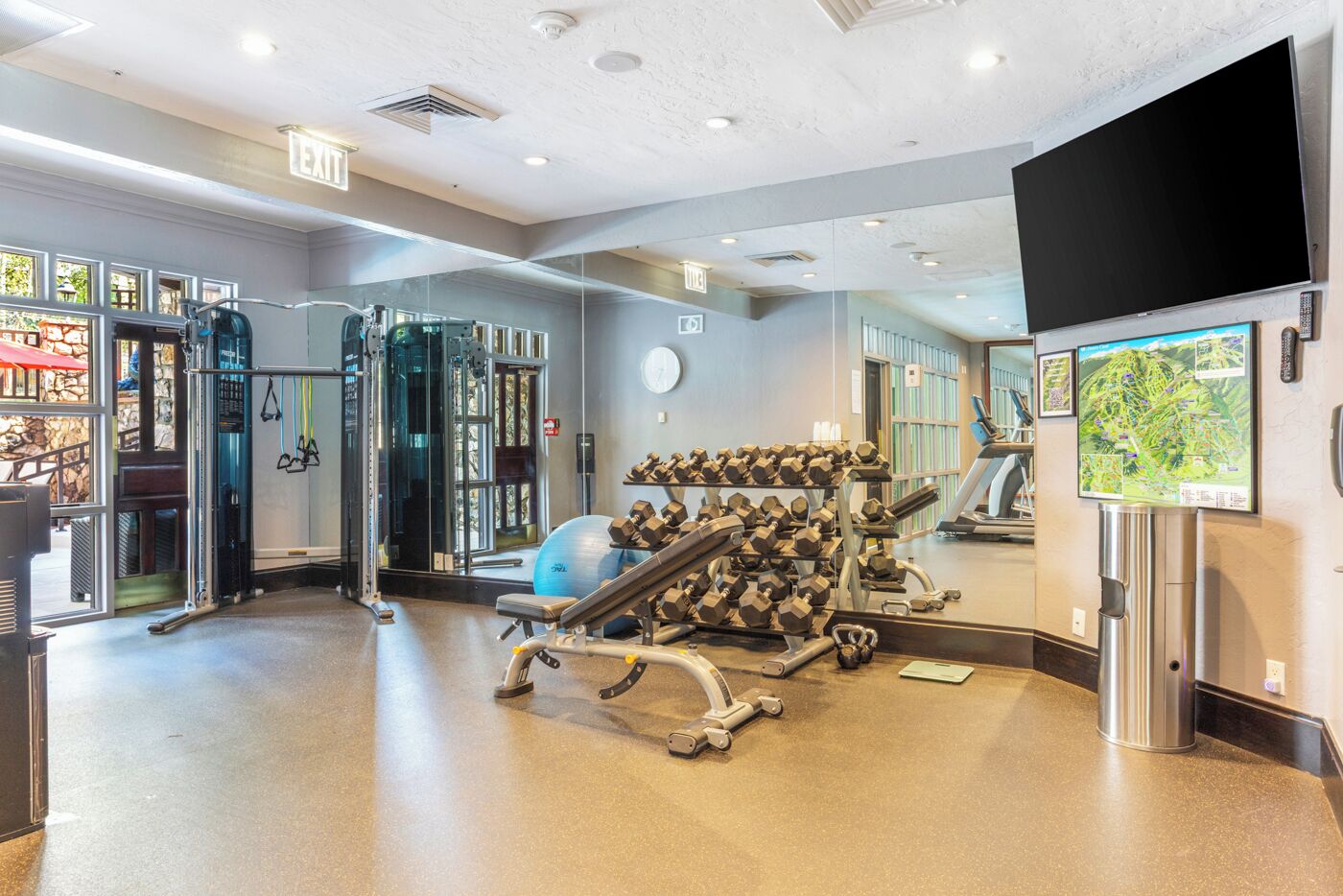 A gym with exercise equipment, a treadmill, and a large mirror.