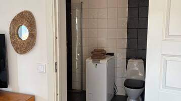 Une salle de bain moderne avec des toilettes blanches, un lave-linge et une douche.