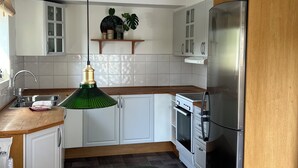 Une cuisine moderne avec des meubles blancs, un réfrigérateur en acier inoxydable et un plan de travail en bois.