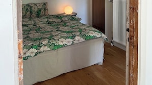 Une chambre à coucher avec un lit, une lampe de chevet, un radiateur et une armoire en bois.