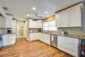 A modern kitchen with white cabinets, a wooden floor, and a tiled backsplash. - Lake Access & Pools! Side-by-side Tampa Homes (Tampa)