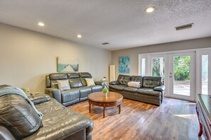 A spacious living room with leather sofas, a wooden coffee table, and large windows offering a view of greenery. - Lake Access & Pools! Side-by-side Tampa Homes (Tampa)