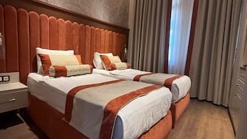 A double bed with a wooden headboard, two bedside tables, and a large window with curtains.