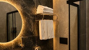 A modern bathroom with a large mirror, a sink, a toilet, and a shower area.