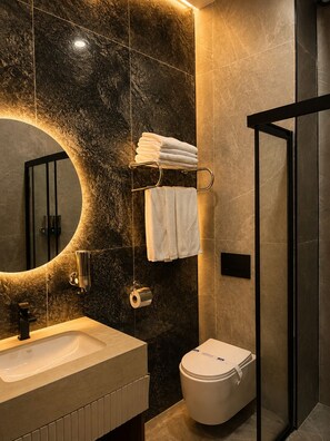 A modern bathroom with a large mirror, a sink, a toilet, and a shower area.
