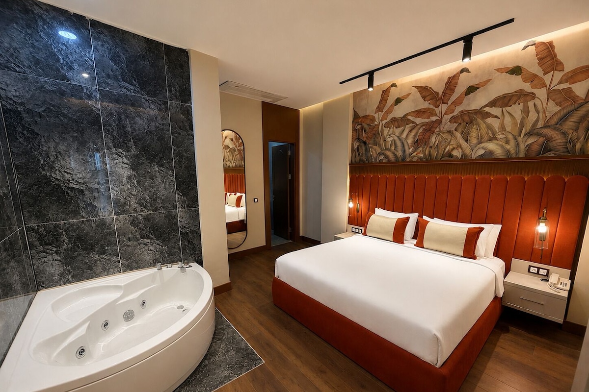Een moderne hotelkamer met een groot bed, een aparte badkamer met een whirlpool en een decoratief behang.