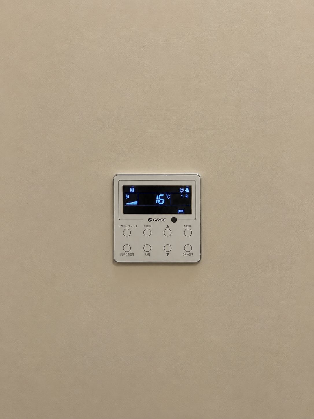 Un termostato fijado a la pared, con pantalla digital, botones de control y el nombre de la marca.