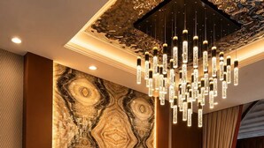 Ein Empfangsschalter mit Wand im Marmor-Design, einer modernen Chandelier und einer Kakteenpflanze.
