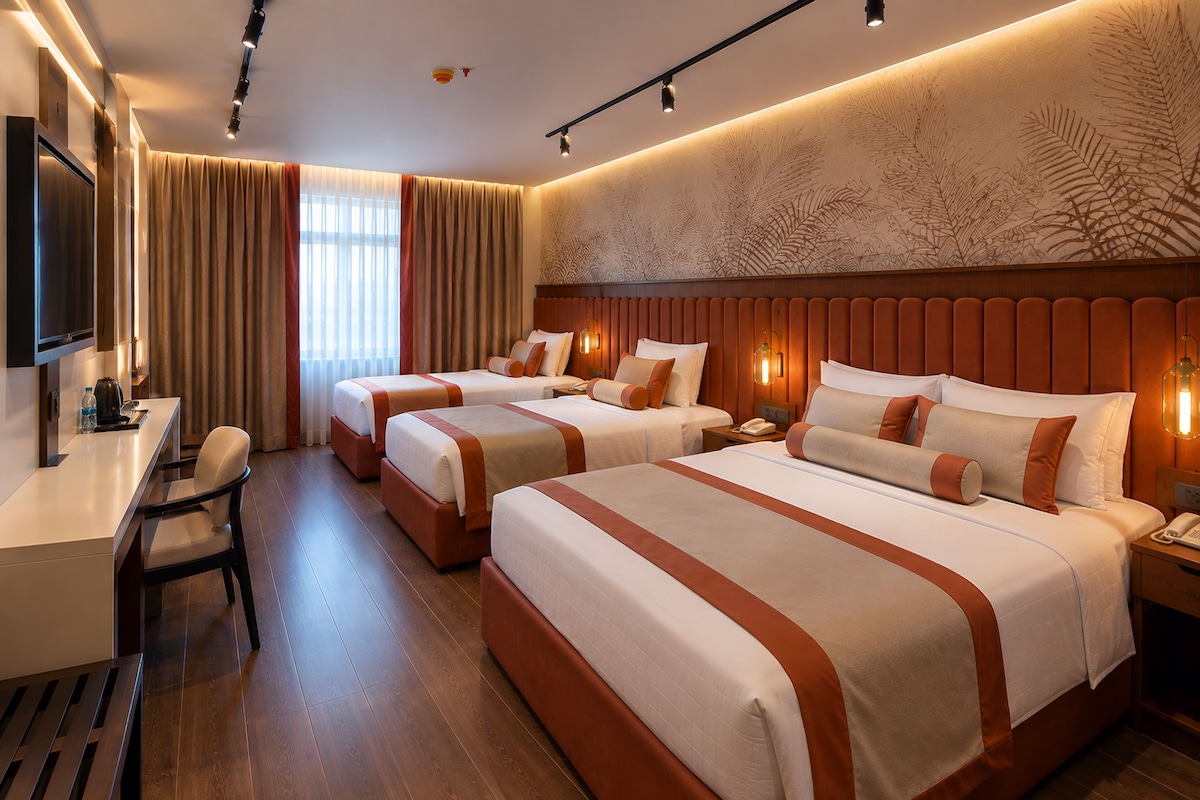A hotel room with three beds, a desk, and a television.