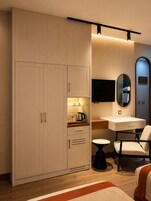 Un dormitorio moderno con un armario grande, una mesita de noche, una silla y un televisor de pantalla plana montado en la pared.