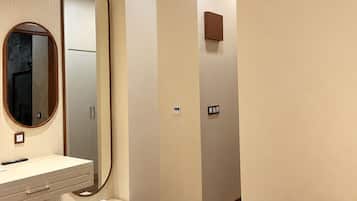 A modern bathroom with a vanity, mirror, and a towel on the floor.