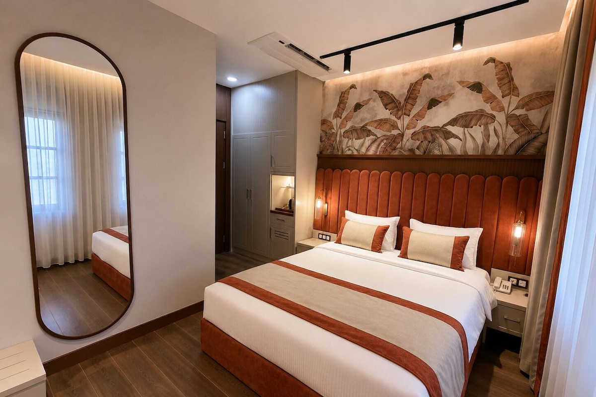 Een hotelkamer met een groot bed, een spiegel, een kledingkast en een muur met een bladmotief.