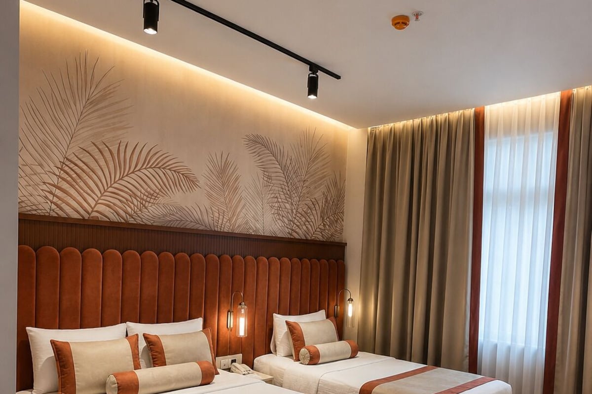 Een hotelkamer met twee bedden, een houten hoofdbord, een bureau en een stoel.