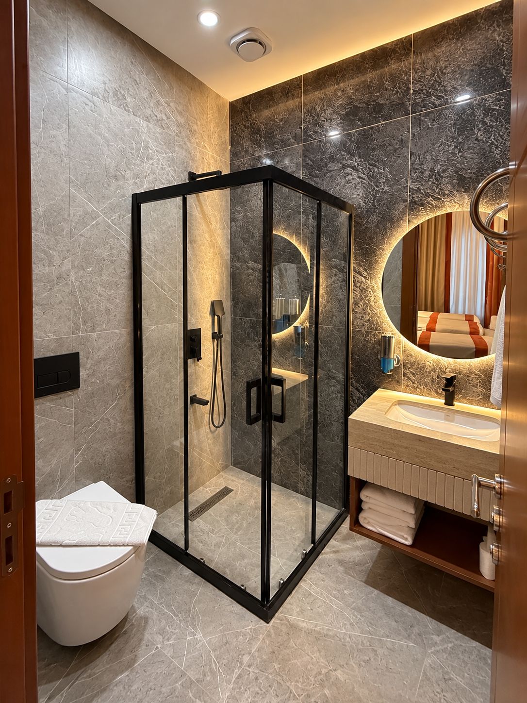A modern bathroom with a glass-enclosed shower, a toilet, and a vanity with a mirror.