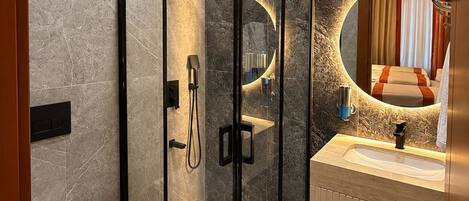 A modern bathroom with a glass-enclosed shower, a toilet, and a vanity with a mirror.