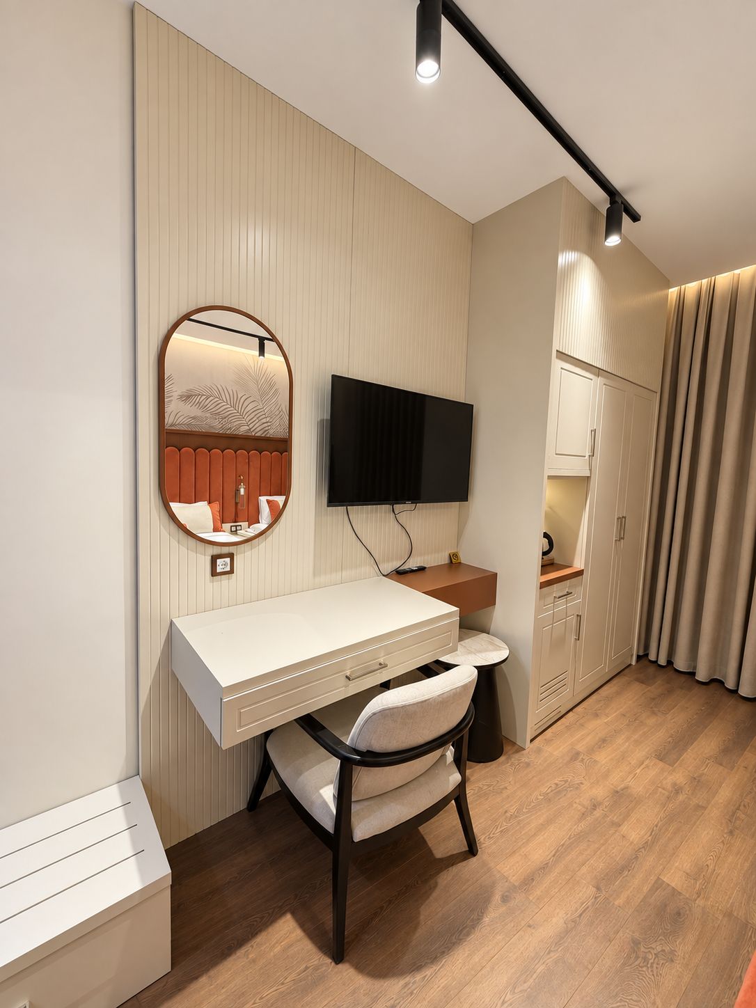 Ein modernes Schlafzimmer mit Schreibtisch, Stuhl, Fernseher, Kleiderschrank und Vorhängen.