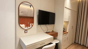 A modern bedroom with a desk, chair, television, wardrobe, and curtains.