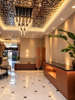 A hotel lobby with a reception desk, seating area, and a decorative ceiling.