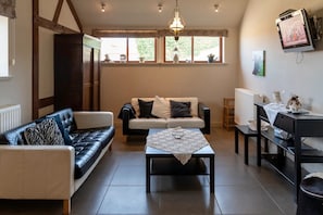 A cozy living room with a sofa, a coffee table, and a television. - Duplex Stay at the Alfonsine Farm (Heers)